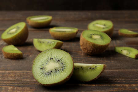 Delicious ripe many kiwi fruit and kiwi in a cut on a brown wooden table. close-up.の写真素材