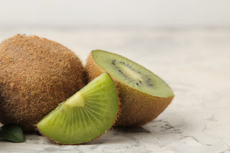 Delicious ripe lots of kiwi fruit and kiwi in a cut on a light concrete background. close-up. space...