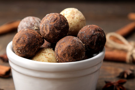 assorted chocolates. candy balls of different types of chocolate on a brown wooden table. cinnamon...