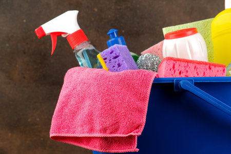 Bottles with cleaning products and detergents in a blue bucket on a dark background. cleaning....