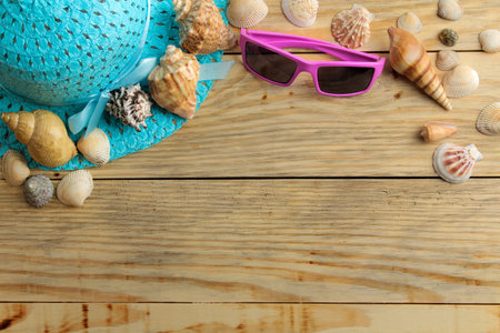 Travel concept Hat, glasses and shells on a natural wooden table. relaxation. holidays. top view....