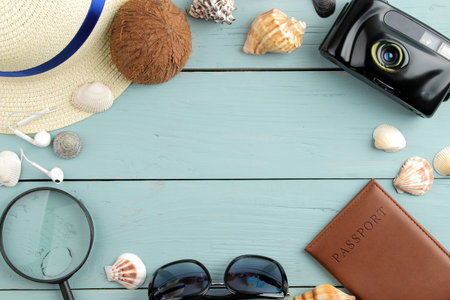 Travel concept camera, passport, glasses. hat and seashells on a blue wooden table. relaxation....