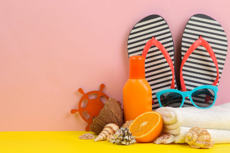 summer accessories with sun glasses, flip flops and shells, on a bright yellow and pink background....
