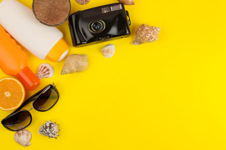 summer accessories with shells, sun glasses, camera on a bright yellow background. top view. space for textの写真素材