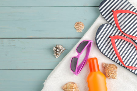 summer accessories. beach accessories. slaps, towel, and sunglasses on a blue wooden table. top...