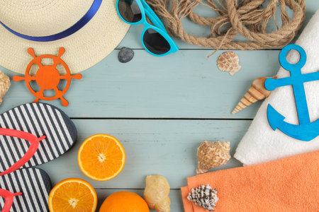 summer accessories. Beach accessories. Slippers, hat, shells, towel, and sunglasses on a blue wooden...