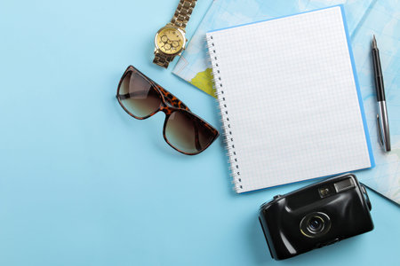 Travel concept. notebook, camera and glasses on a bright blue background. top view. space for text
