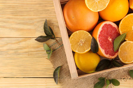 Citrus fruit. various citrus fruits with leaves of lemon, orange, grapefruit in a box on a natural wooden table. top viewの写真素材