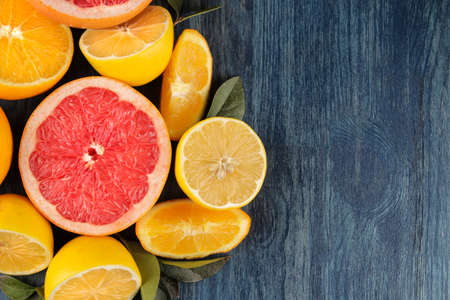 Citrus fruit. Different citrus fruits with leaves of lemon, orange, grapefruit on a blue wooden table. top viewの写真素材