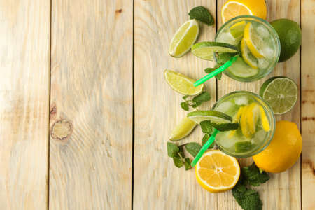 Mojito cocktail in a glass glass with lime, mint and lemon and on a natural wooden table. make a mojito. top viewの写真素材