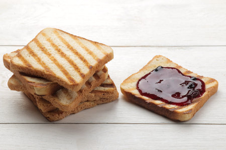 toasts with jam. fried crispy toasts with red jam on a white wooden table.