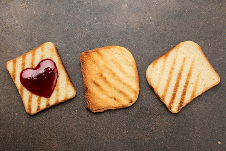 toasts with jam. fried crispy toasts with a red heart made of jam on a dark background. breakfast....