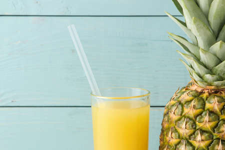 Ripe pineapple fruit and pineapple juice on a blue wooden background. place for text. close-upの写真素材