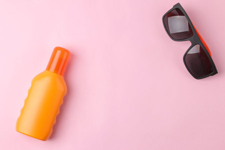 Sunscreen on a bright pink background and sunglasses. summer. vacation. top view. space for text