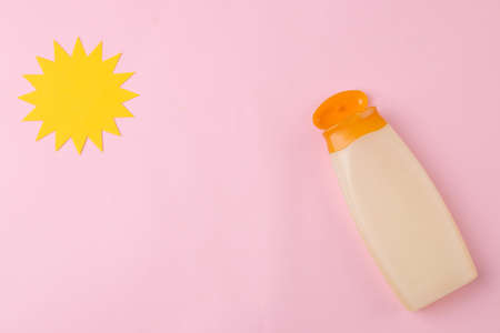 Sunscreen and paper sun on a bright pink background. summer. vacation. Sun protection. top view.の写真素材