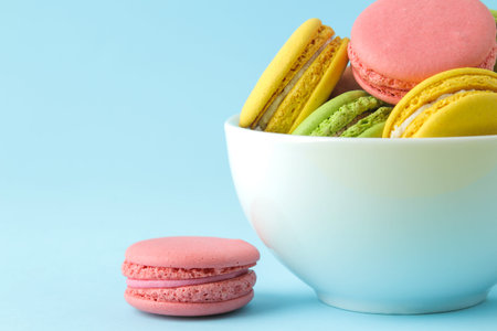 Macarons french multicolored macaroons cakes in a cup. small french sweet cake on bright blue...