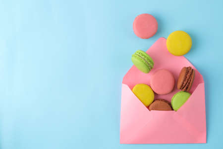 Macarons french multicolored macaroons cakes in envelope. small french sweet cake on bright blue background. Dessert. Sweets. top view.の写真素材