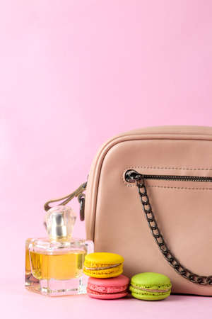 Stylish fashionable pink bag and French macaroons and perfume cakes on a bright trendy pink background. female accessory conceptの写真素材