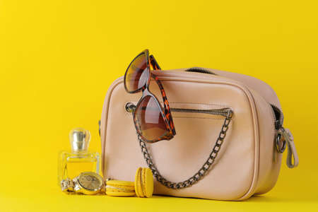 Stylish fashionable pink bag and women's cosmetics and accessories on a bright trendy yellow background. female accessory concept.の写真素材