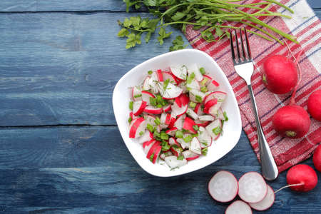 Salad of fresh radishes and fresh herbs on a blue wooden table. Spring vegetable salad. ingredients for cooking salad. top viewの写真素材