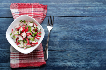 Salad of fresh radishes and fresh herbs on a blue wooden table. Spring vegetable salad. top view