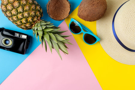 Large ripe pineapple fruit and summer accessories on a bright yellow, blue and pink background....