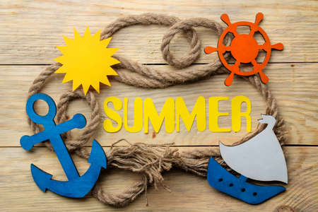 Word summer of paper yellow letters and rope marine and marine accessories on a natural wooden background. summer. vacation. relaxation. top viewの写真素材