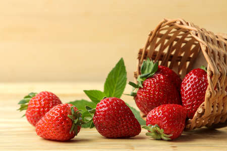 Ripe, delicious strawberries. red berry strawberries in a wicker basket on a natural wooden tableの写真素材