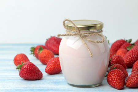 delicious strawberry yogurt in a jar and fresh ripe strawberries on a light blue wooden table.の写真素材