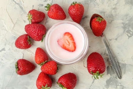 delicious strawberry yogurt in a jar and fresh ripe strawberries on a light concrete table. top viewの写真素材