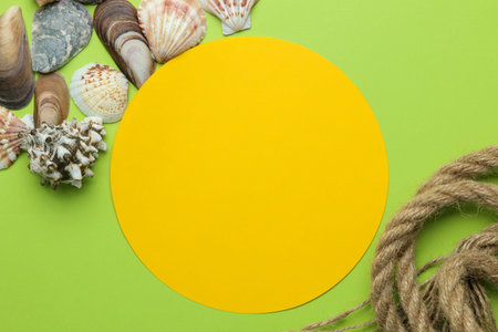 Summer frame. Paper frame for your text, rope and seashells on a bright green background. top view
