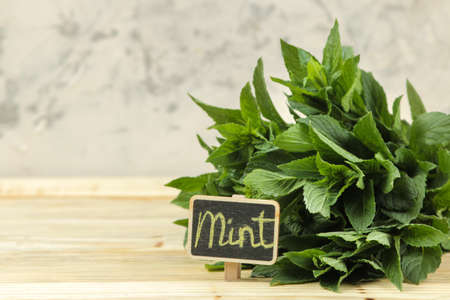 Mint. Leaves and branches of fresh green wild mint with a sign with the text on a wooden natural table.の写真素材