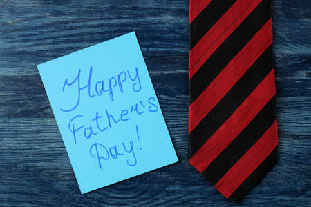 Happy father's day. text on paper and man's tie on a blue wooden table. men's holiday. top viewの写真素材