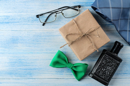 happy father's day. men's accessory tie perfume, glasses and a light blue wooden background. top...