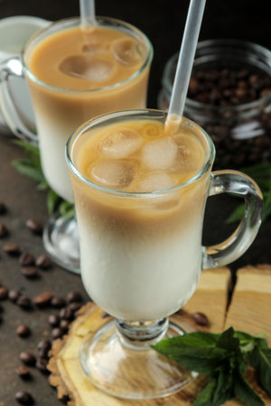 Ice latte or Iced coffee with milk and ice cubes in a glass beaker against a dark background....