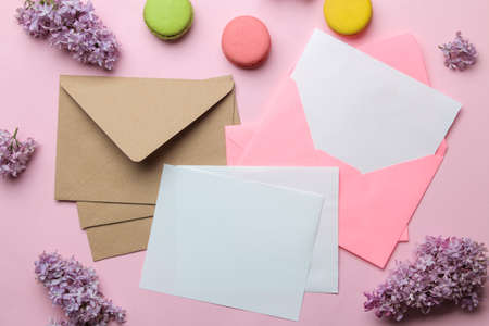 Pink envelope with a blank for text and a branch of lilac and macarons on a bright trendy pink background. top viewの写真素材