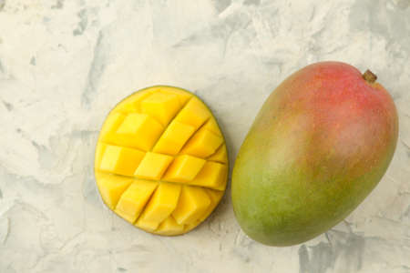 Ripe fresh mango fruit and pieces and leaves on a light background. tropical fruit. top view. space for textの写真素材