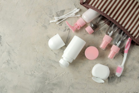 A set of cosmetics and personal care products for travel in a cosmetic bag on a light concrete...