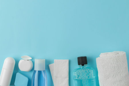 A set of cosmetics and personal care products for traveling on a gentle light blue background. top...