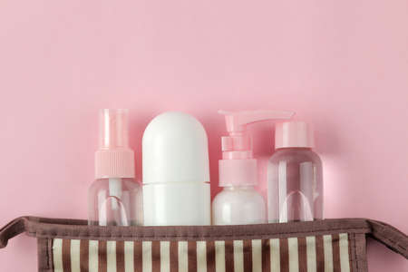 A set of cosmetics and personal care products for travel in a cosmetic bag on a light pink background. top view. travel cosmeticsの写真素材