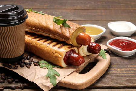 French hot dogs. Tasty hot dogs on the board and coffee on a brown wooden table. fast food street food. sausages in a bun.の写真素材