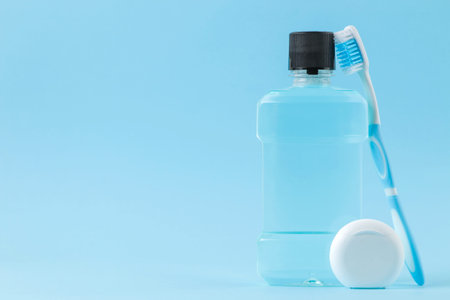 Oral hygiene. Toothbrush, dental floss and mouthwash for teeth and mouth on a gentle blue...