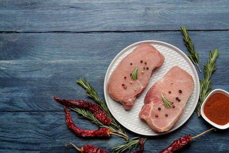 Raw pork steak on a plate, meat and ingredients for cooking, spices herbs and vegetables on a light background. top viewの写真素材