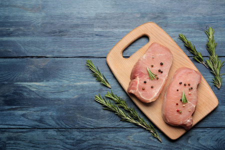 Raw pork steak on the board, meat and ingredients for cooking, spices herbs and vegetables on a...
