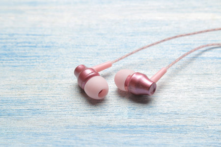 Small pink headphones on a light blue wooden background. close-up