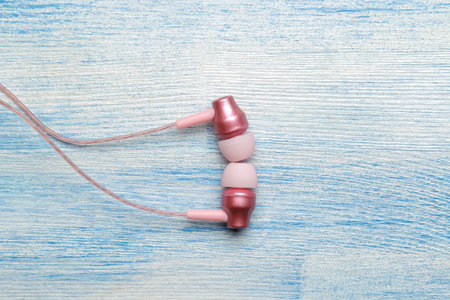 Small pink headphones on a light blue wooden background. view from above