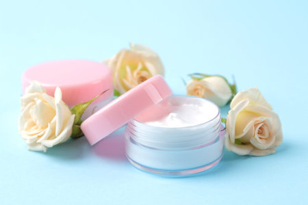 cosmetics for face and body. Cream in pink bottles with fresh roses on a gentle blue background....