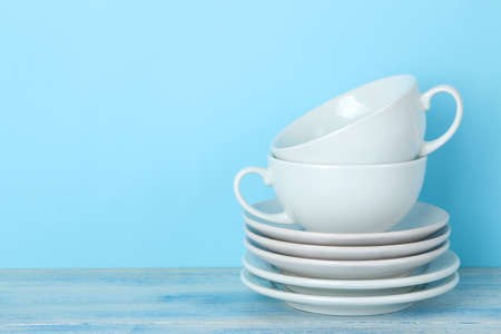 Piles of white ceramic tableware, saucers and cups on a gentle blue background. kitchenware.の写真素材