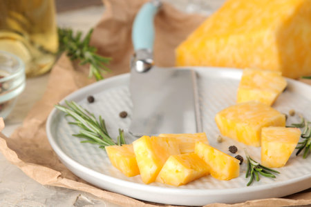 Slices of delicious marble cheese with a sprig of rosemary and cheese knife on a plate on a light...