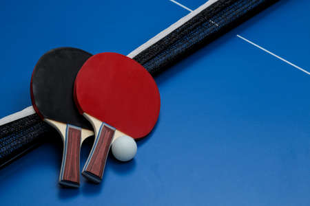 Two table tennis rackets. Table tennis rackets and a ball on a blue tennis tableの写真素材
